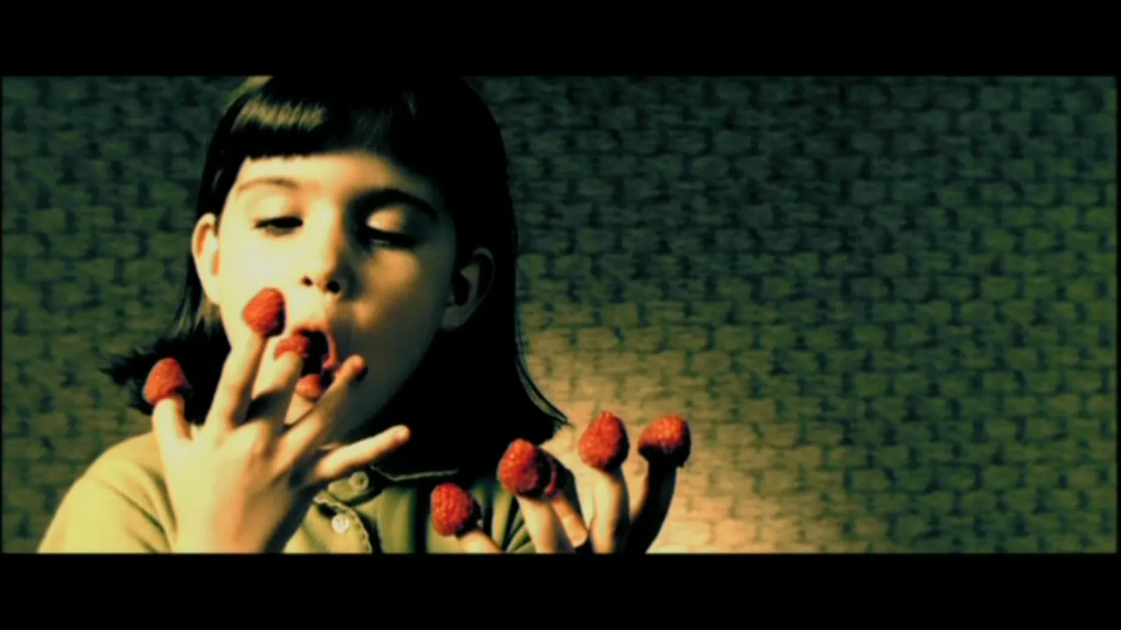 A playful moment: a girl with raspberries on her fingertips, against a green and golden background